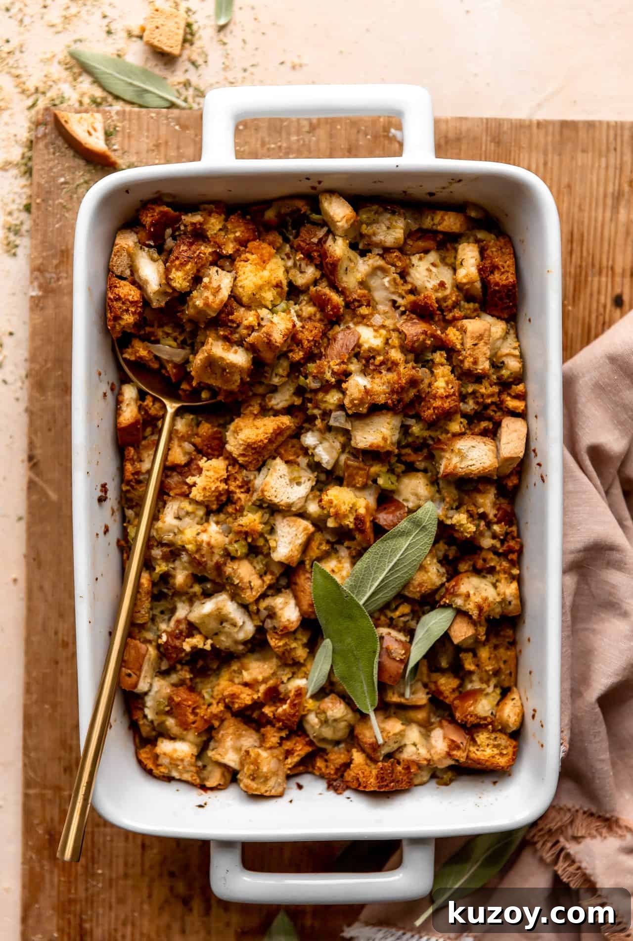 Dish with baked cornbread dressing topped with fresh sage leaves.