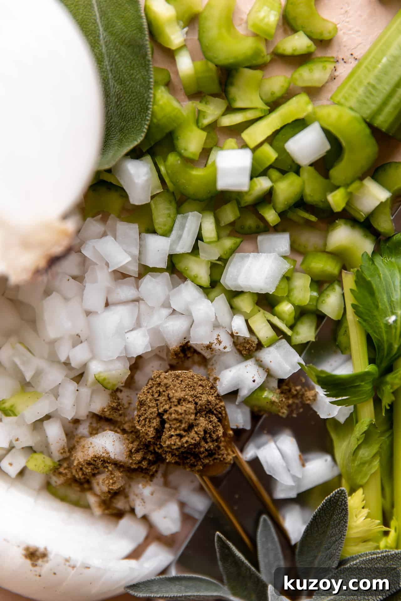 Ingredients needed to make homemade cornbread dressing. Sliced celery, onion, dried herbs, fresh herbs.