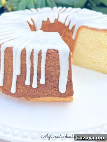 Sour cream pound cake, sliced, glazed, and on a white pedestal.