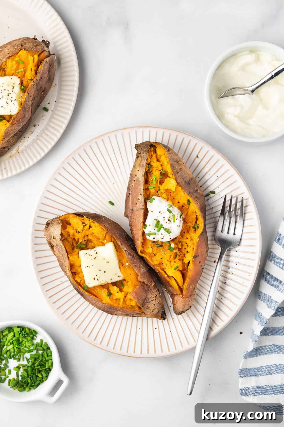 Overhead view of two slow cooker sweet potatoes with butter, sour cream, and chives.