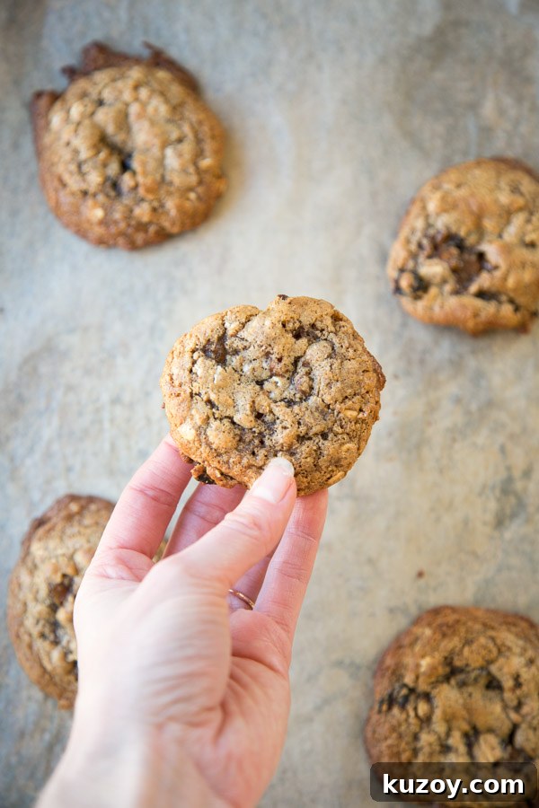 hand holding healthy low sugar oatmeal cookies over a sheet pan