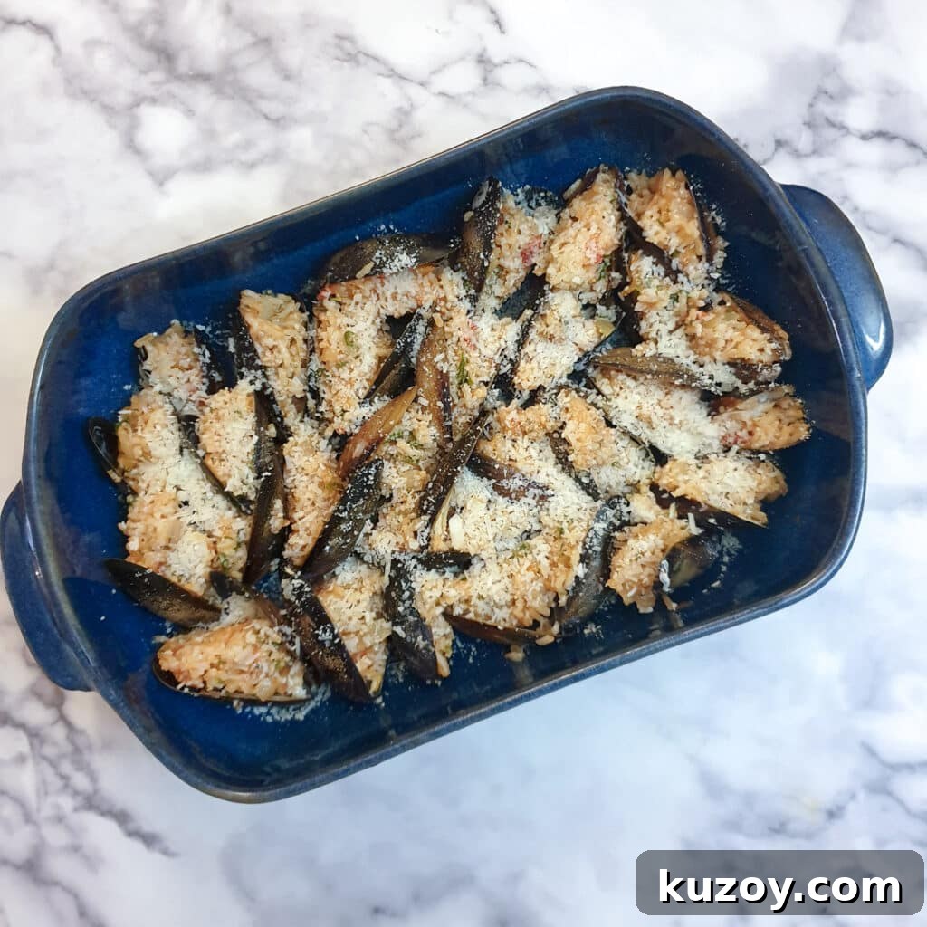 Stuffed mussels in a baking dish covered in browned parmesan cheese.