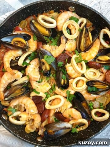 A pan of Spanish paella garnished with prawn, mussels and calamari rings.