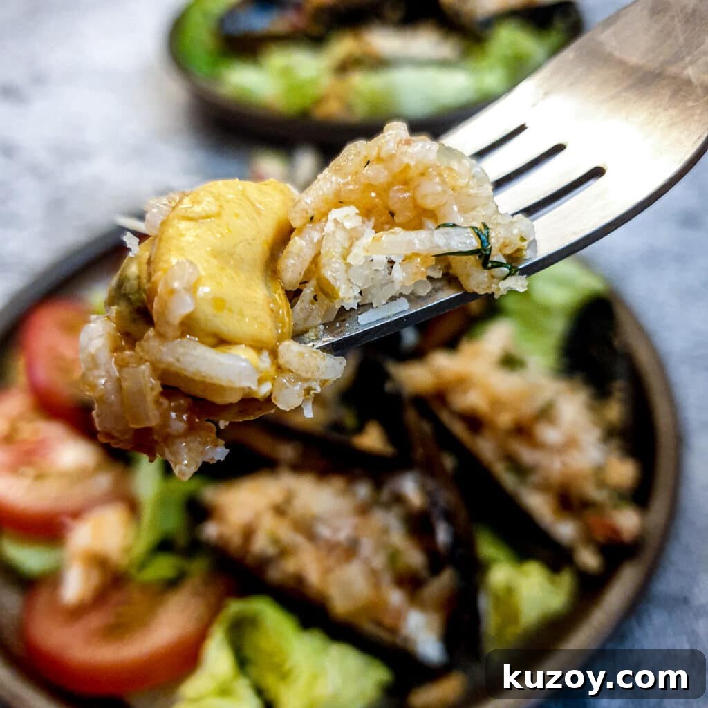 Close up of a mussel with rice stuffing on a fork.