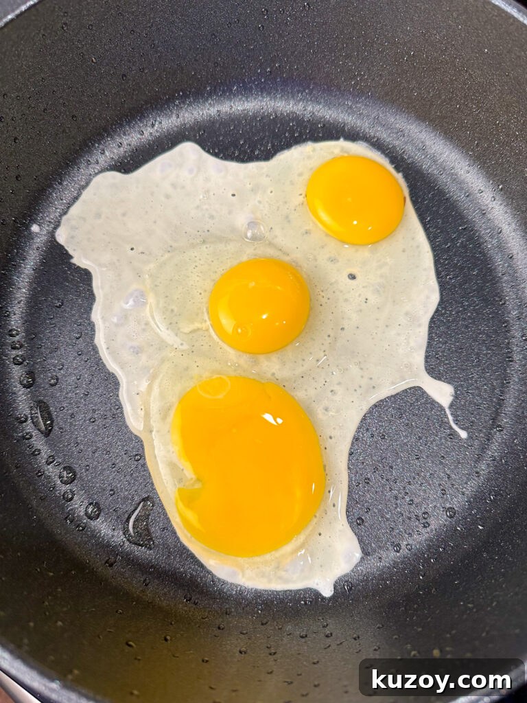 Three eggs frying in a pan.