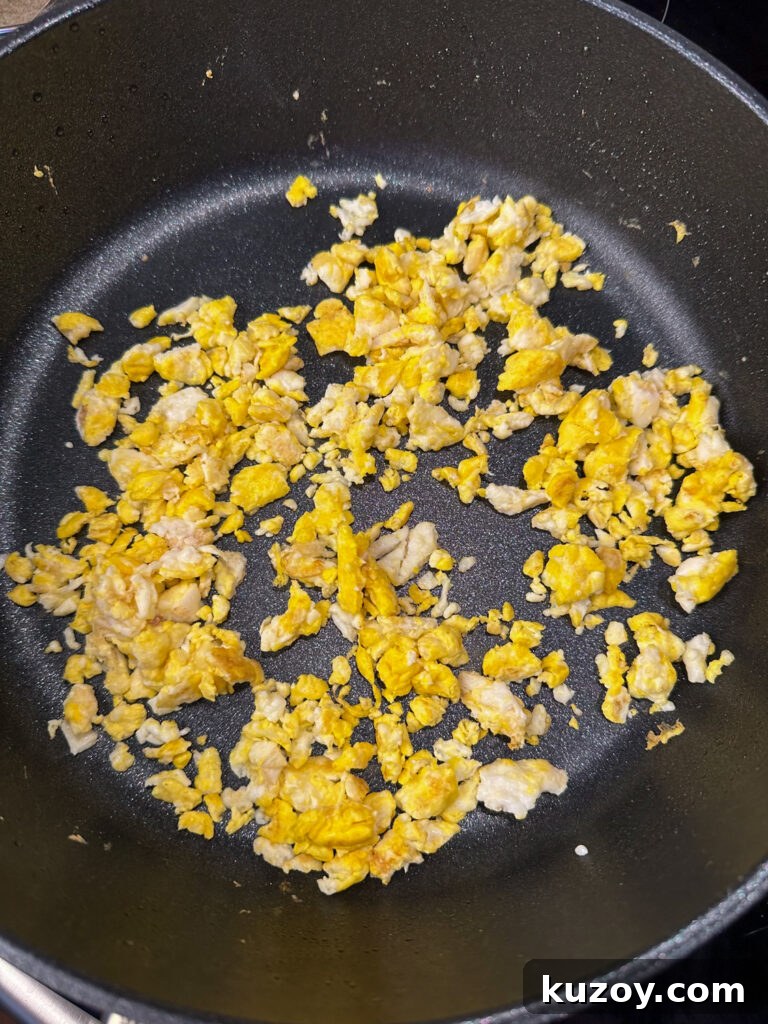 Fried eggs chopped up into small pieces in a skillet.