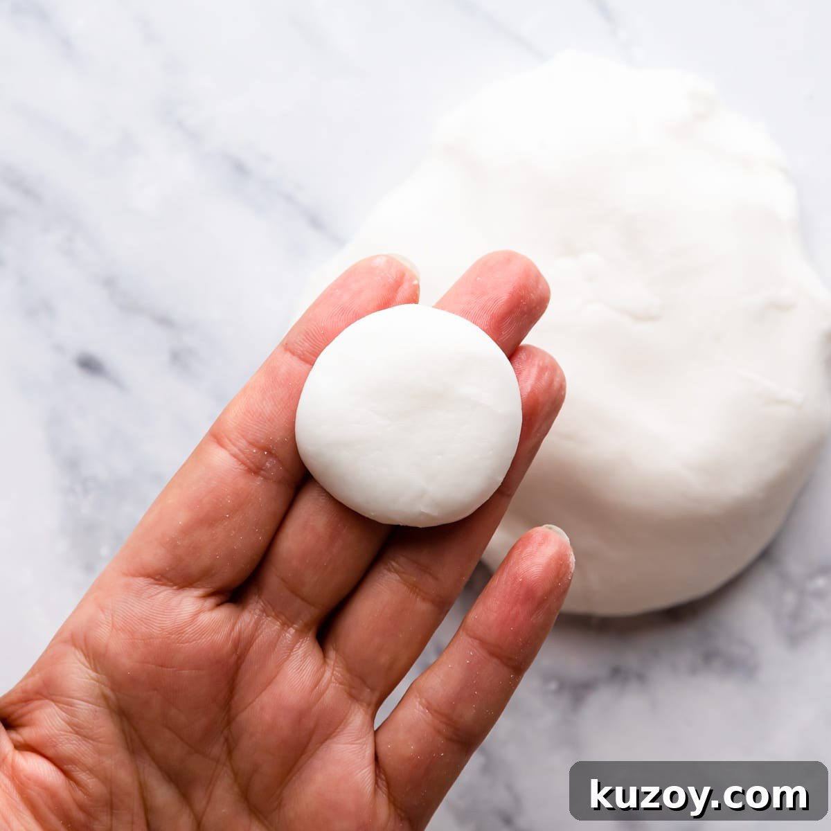 small piece of dough for mint creams shaped into flat disc held on someone's hand.