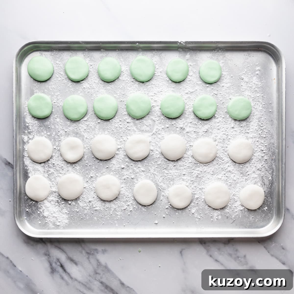 silver metal tray dusted with icing sugar and filled with white and green peppermint cream patties.