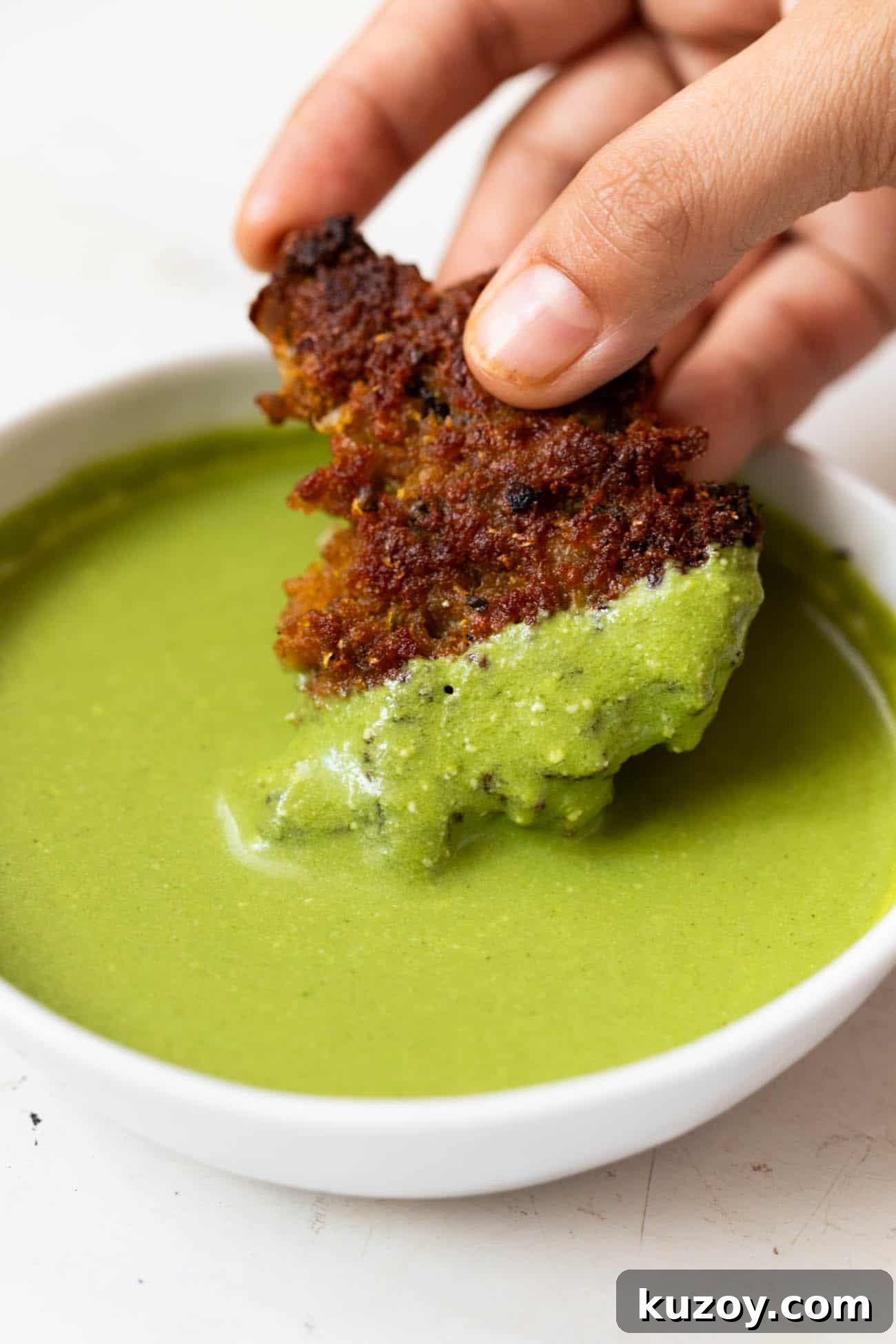 Chapli kebab being dipped into mint chutney