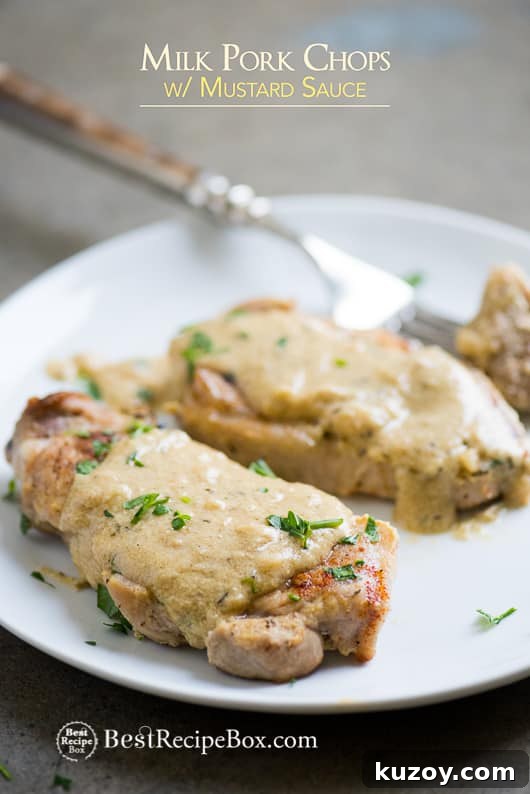 Juicy Pork Chops Braised in Milk with Mustard Sauce on a plate with fork 