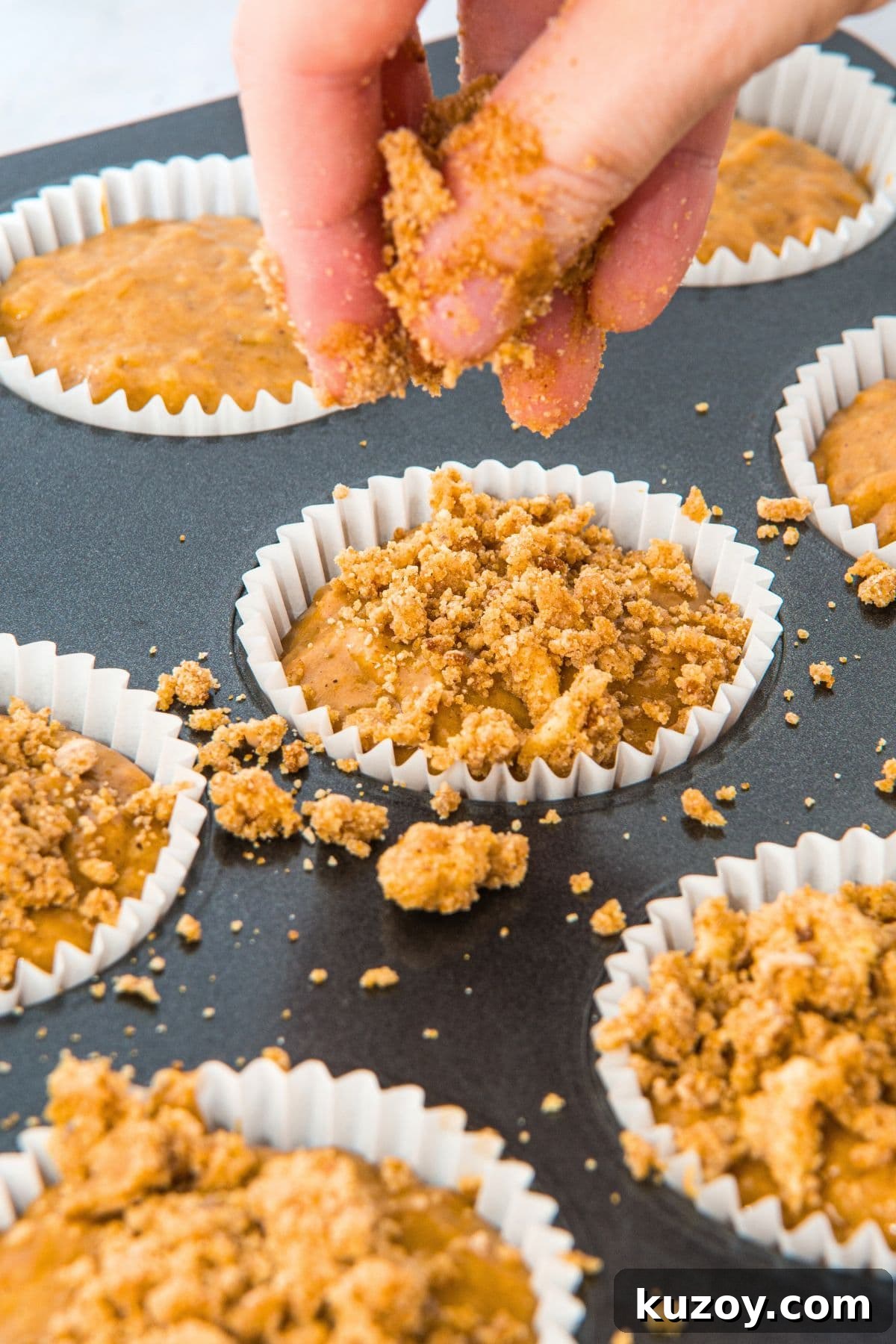 Sprinkling streusel topping on top of muffin batter