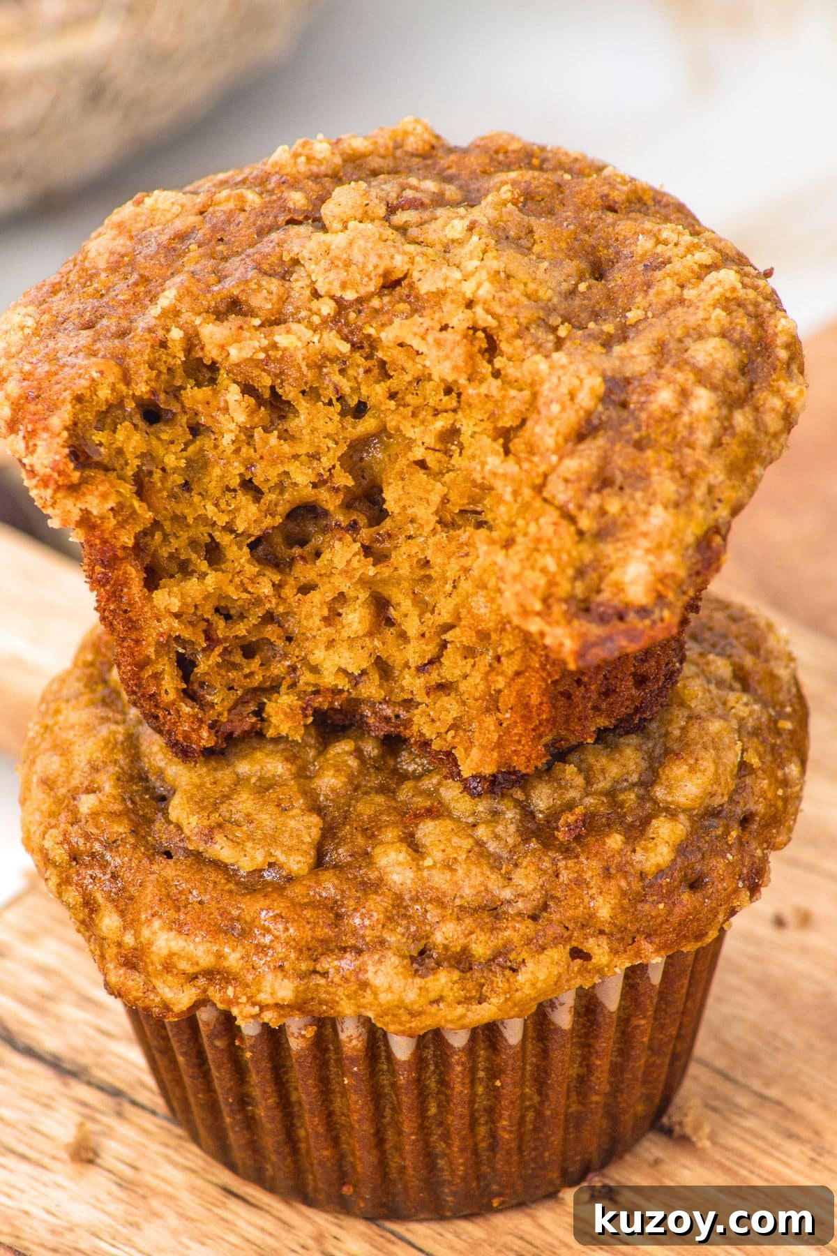 Half-eaten pumpkin spice banana muffins stacked on each other
