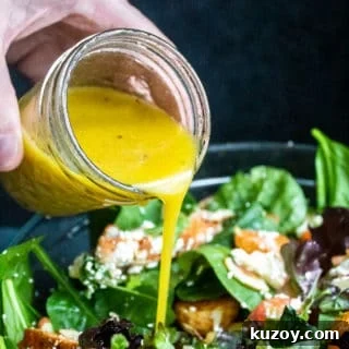 Honey Dijon Vinaigrette dressing being poured onto a bowl of salad.