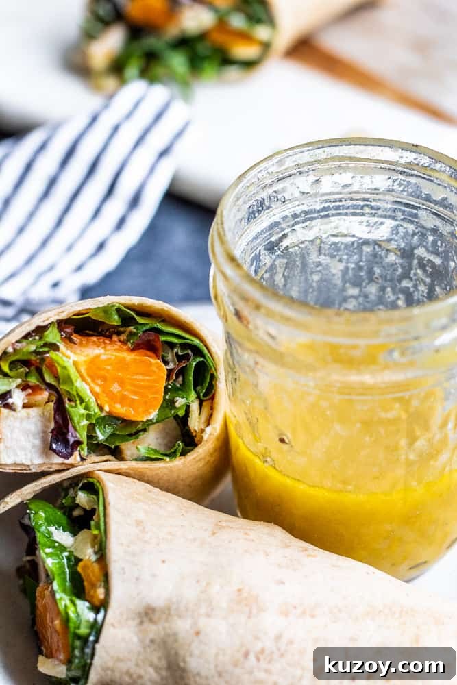 White plate with wrap and a glass mason jar of dressing.