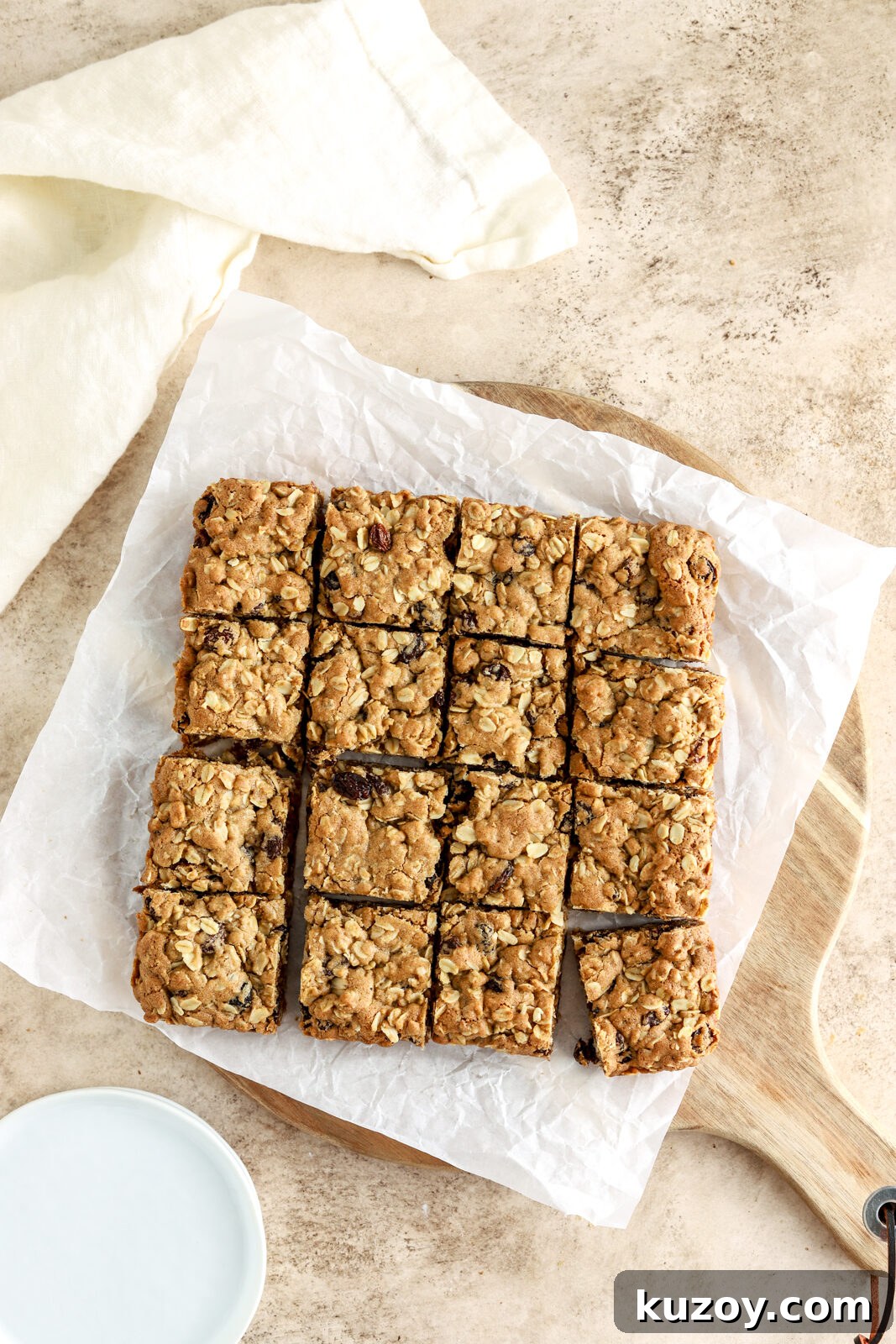 Oatmeal raisin squares on a board lined with parchment paper.