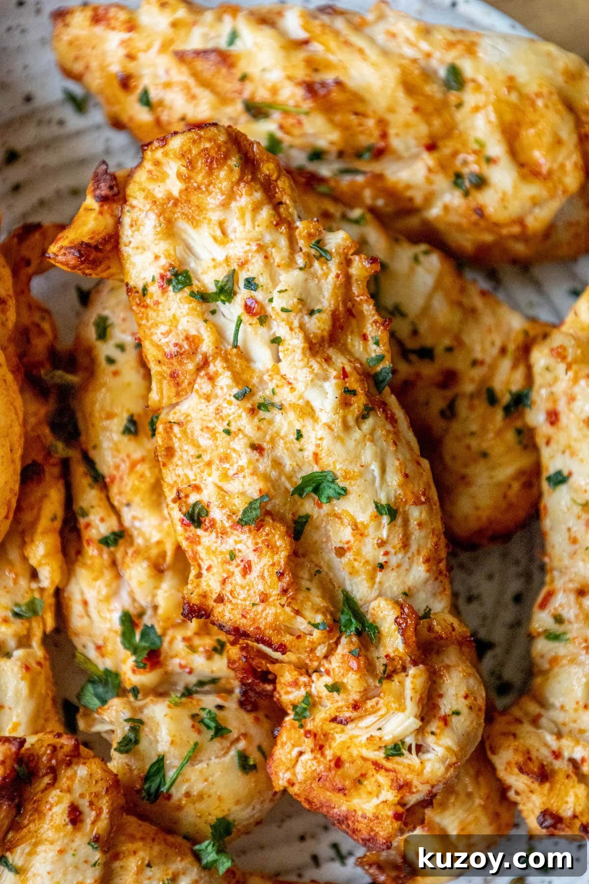 grilled chicken in ajika seasoning on a white plate on a table with chopped cilantro on top