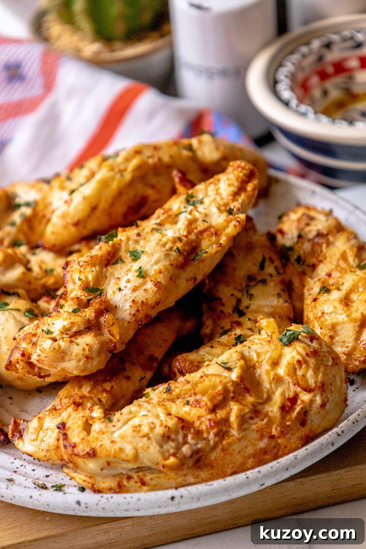 grilled chicken in ajika seasoning on a white plate on a table with chopped cilantro on top