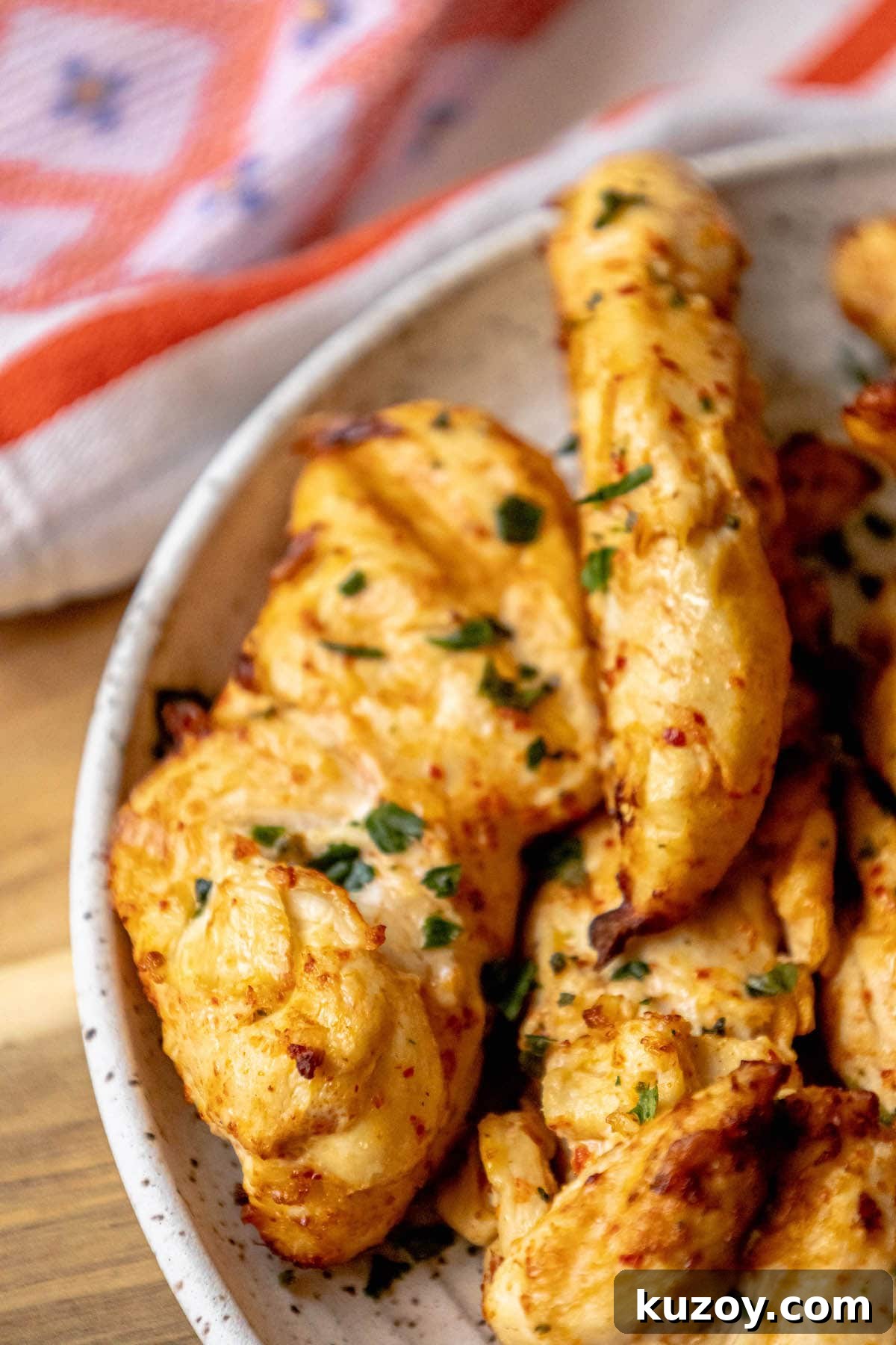 grilled chicken in ajika seasoning on a white plate on a table with chopped cilantro on top