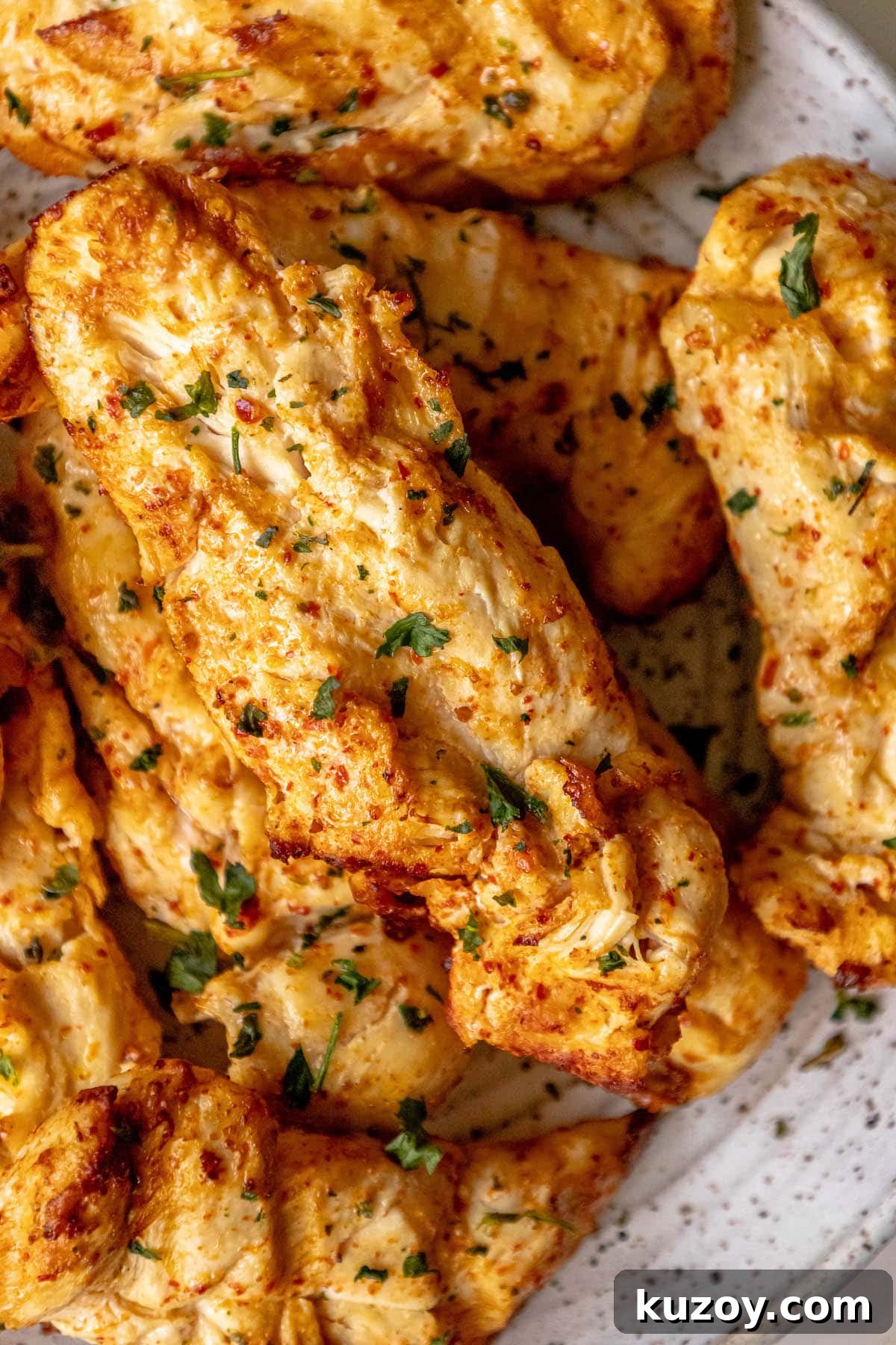 grilled chicken in ajika seasoning on a white plate on a table with chopped cilantro on top