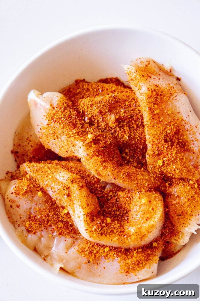 raw chicken tenders in a bowl with ajika seasoning 